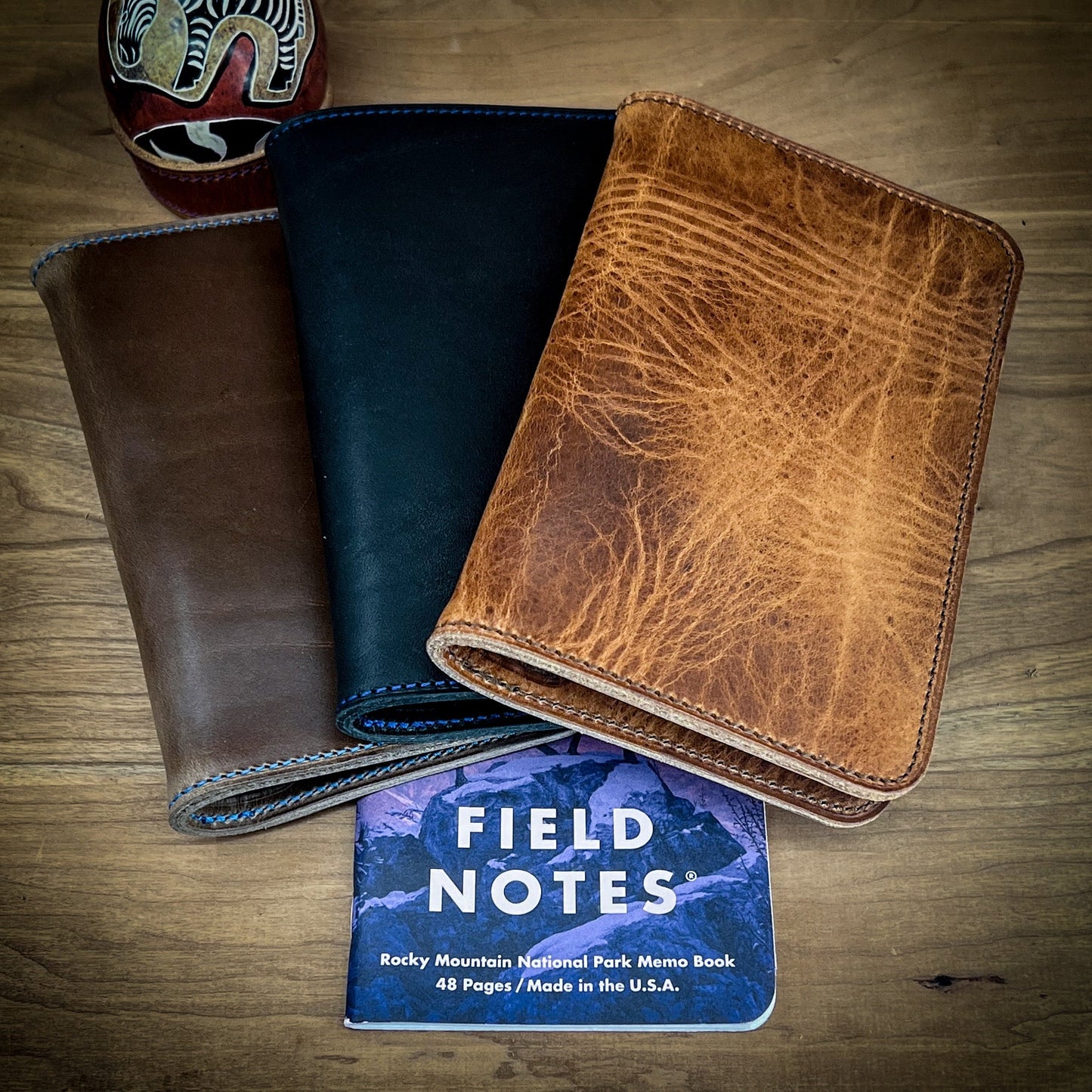 A set of three handmade Horween Leather notebook covers including Natural CXL Horween, Black CXL Horween and English Tan Horween leathers.  Handmade by Custom Leather and Pen in Houston, TX