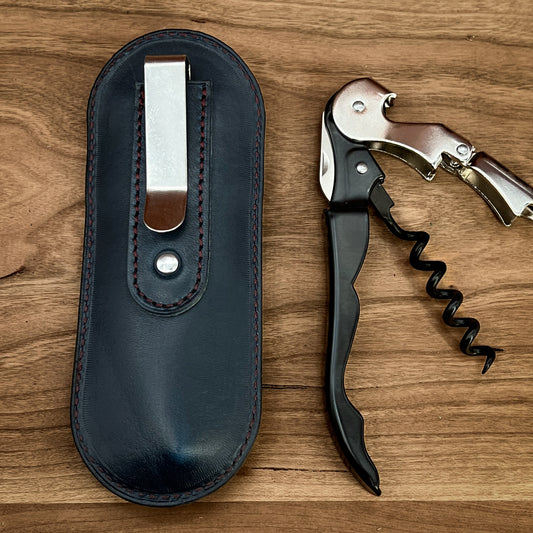 Shown is the back side of a Handmade Leather Corkscrew Case and Pulltap Corkscrew.  The photo features the slide on belt clip to fasten the case.  The corkscrew case is made in cobalt blue horween leather with burgundy stitching.  this is a handmade item by Custom Leather and Pen in Houston, Texas